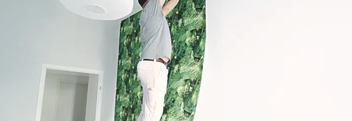 Person bringt Tapete mit Leiter an